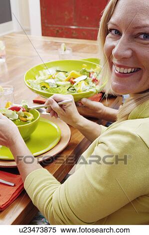 Stock Photography - Portrait of a mature woman sitting at the dining table and smiling. Fotosearch