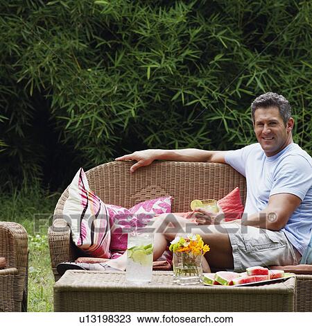 Portrait of a mid adult man sitting on a couch and holding a glass of lemonade View Large Photo Image Stock Image - Portrait of a mid adult man sitting on a couch and holding a glass of lemonade. Fotosearch
