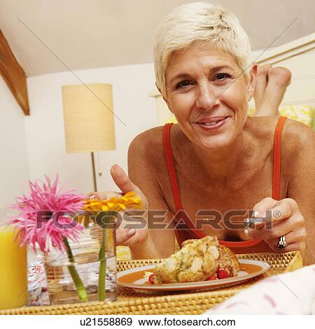 Portrait of a senior woman eating breakfast in bed View Large Photo Image Stock Photo - Portrait of a senior woman eating breakfast in bed. Fotosearch