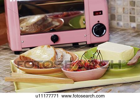 Stock Image - Close-up of cherries with bread and butter in a tray in front of a microwave. Fotosearch