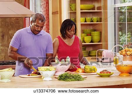 Mature couple cutting vegetables in the kitchen View Large Photo Image Stock Photograph - Mature couple cutting vegetables in the kitchen. Fotosearch