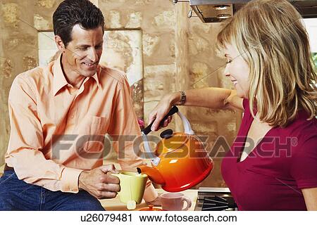 Mature man holding a cup with a mature woman pouring tea into it View Large Photo Image Stock Image - Mature man holding a cup with a mature woman pouring tea into it. Fotosearch