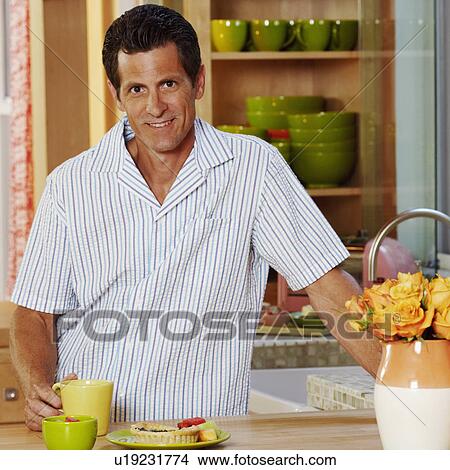 Portrait of a mature man standing in a kitchen and smiling View Large Photo Image Picture - Portrait of a mature man standing in a kitchen and smiling. Fotosearch