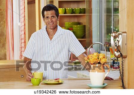 Portrait of a mature man standing in a kitchen and smiling View Large Photo Image Stock Photograph - Portrait of a mature man standing in a kitchen and smiling. Fotosearch