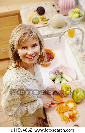 Portrait of a mature woman cutting yellow bell peppers in the kitchen View Large Photo Image Stock Image - Portrait of a mature woman cutting yellow bell peppers in the kitchen. Fotosearch