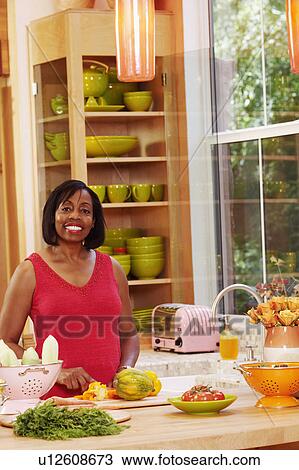 Portrait of a mature woman cutting vegetables in the kitchen and smiling View Large Photo Image Stock Image - Portrait of a mature woman cutting vegetables in the kitchen and smiling. Fotosearch
