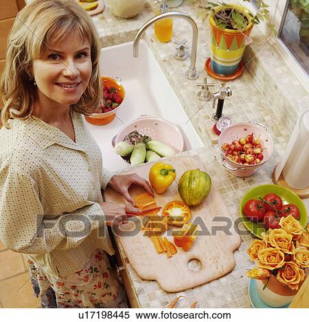 Portrait of a mature woman cutting yellow bell peppers in the kitchen View Large Photo Image Stock Photography - Portrait of a mature woman cutting yellow bell peppers in the kitchen. Fotosearch