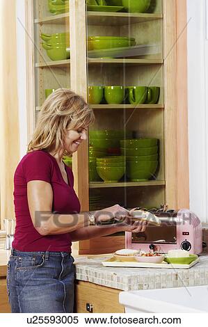 Side profile of a mature woman applying butter on a slice of bread in the kitchen View Large Photo Image Stock Photography - Side profile of a mature woman applying butter on a slice of bread in the kitchen. Fotosearch