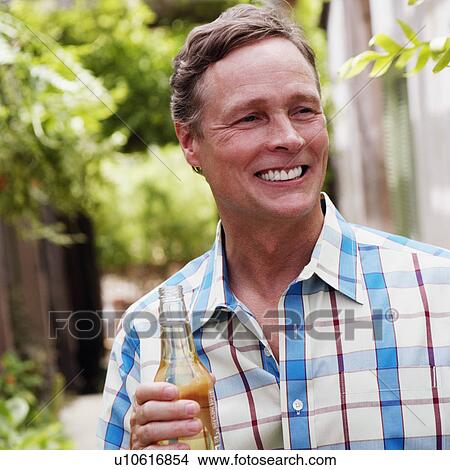 Picture - Close-up of a mature man holding a bottle of white wine. Fotosearch