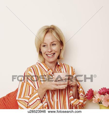 Stock Photograph - Close-up of a mature woman holding a cup and smiling. Fotosearch