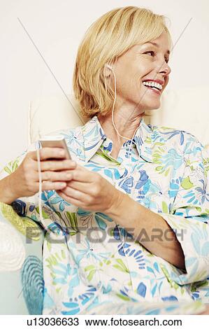 Close-up of a mature woman holding an MP3 player and smiling View Large Photo Image Stock Image - Close-up of a mature woman holding an MP3 player and smiling. Fotosearch
