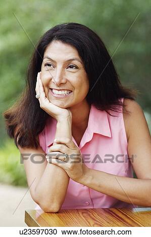 Stock Image - Close-up of a mature woman with her hand on her chin. Fotosearch