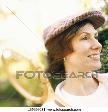 Close-up of a mid adult woman holding a tennis racket and smiling View Large Photo Image Stock Image - Close-up of a mid adult woman holding a tennis racket and smiling. Fotosearch