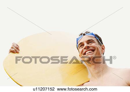 Low angle view of a mature man carrying a surfboard and smiling View Large Photo Image Stock Image - Low angle view of a mature man carrying a surfboard and smiling. Fotosearch