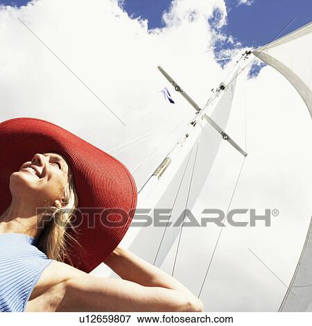 Stock Photo - Low angle view of a mature woman smiling in a sailboat. Fotosearch