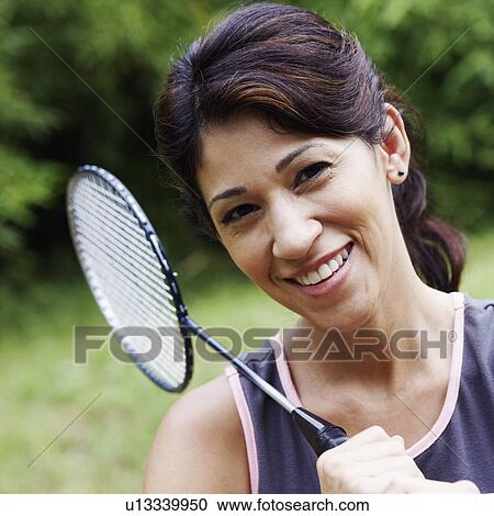 Stock Image - Portrait of a mature woman holding a badminton racket and smiling. Fotosearch