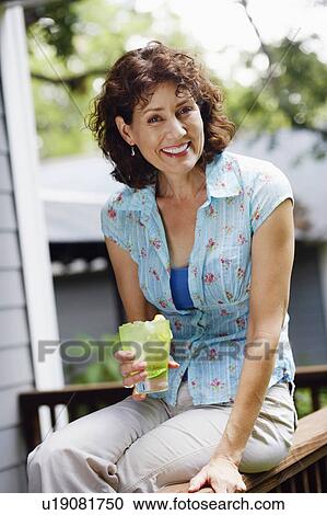 Portrait of a mature woman holding a glass of lemonade View Large Photo Image Stock Image - Portrait of a mature woman holding a glass of lemonade. Fotosearch