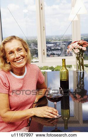 Stock Photo - Portrait of a mature woman holding a glass of wine and smiling. Fotosearch
