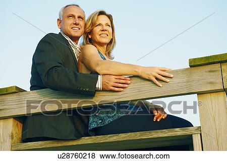 Low angle view of a mature couple sitting by a railing View Large Photo Image Stock Photo - Low angle view of a mature couple sitting by a railing. Fotosearch