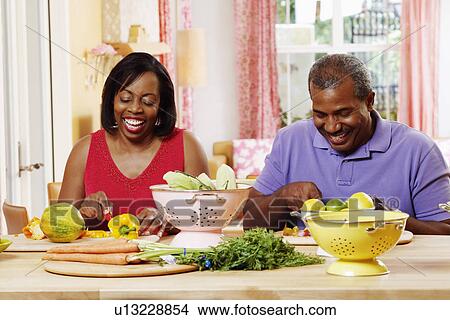 Mature couple cutting vegetables and smiling View Large Photo Image Picture - Mature couple cutting vegetables and smiling. Fotosearch