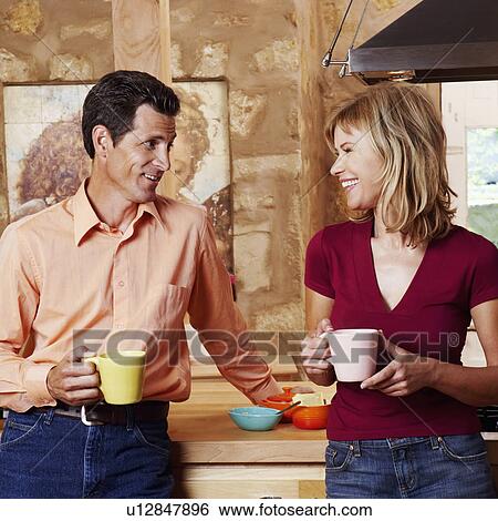 Stock Photograph - Mature couple holding cups and smiling. Fotosearch
