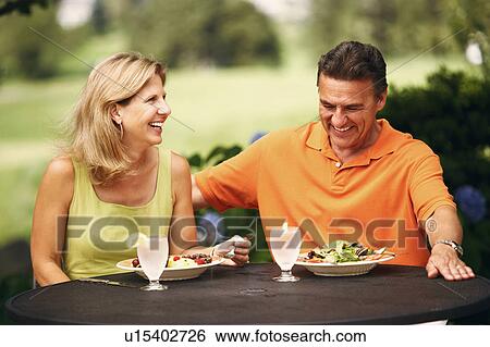 Stock Photograph - Mature couple sitting at the table with plates of salad in front of them. Fotosearch