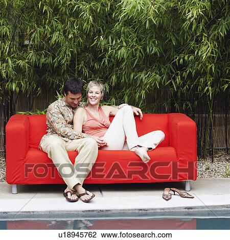 Mature couple sitting on a couch and smiling View Large Photo Image Stock Image - Mature couple sitting on a couch and smiling. Fotosearch