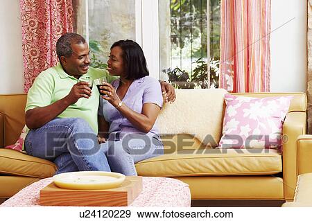 Mature couple sitting on a couch and toasting with glasses View Large Photo Image Stock Photo - Mature couple sitting on a couch and toasting with glasses. Fotosearch