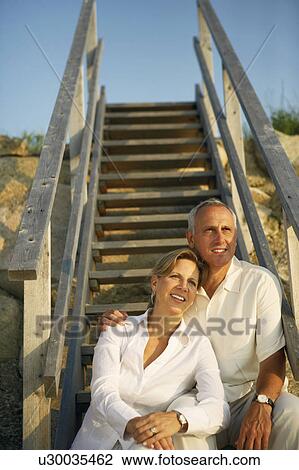 Stock Image - Mature couple sitting on a staircase and looking away. Fotosearch