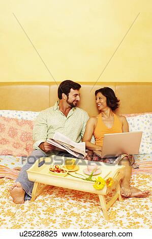 Stock Photography - Mature couple sitting on the bed and looking at each other. Fotosearch