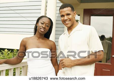 Stock Image - Portrait of a couple standing in a balcony and smiling. Fotosearch