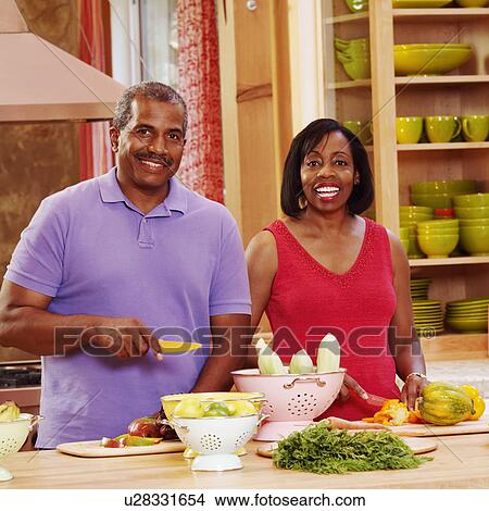 Portrait of a mature couple cutting vegetables in the kitchen and smiling View Large Photo Image Picture - Portrait of a mature couple cutting vegetables in the kitchen and smiling. Fotosearch