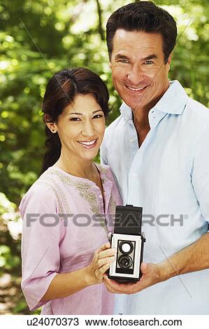 Portrait of a mature couple holding a camera View Large Photo Image Stock Image - Portrait of a mature couple holding a camera. Fotosearch