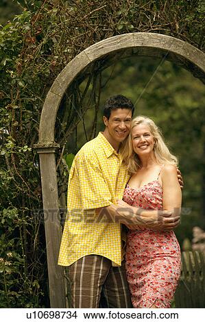 Picture - Portrait of a mature couple standing in the park and smiling. Fotosearch