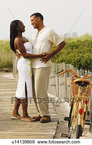 Stock Photo - Side profile of a couple embracing each other and smiling. Fotosearch