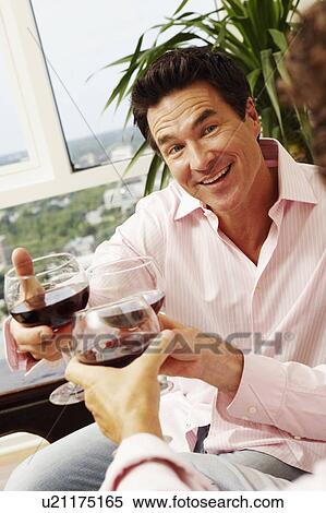 Stock Photography - Close-up of a mature man and two people toasting glasses of wine. Fotosearch