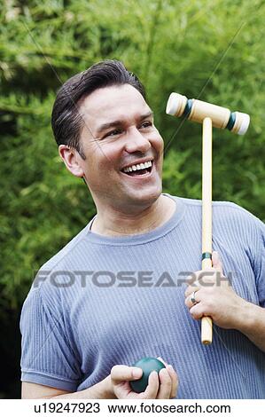 Stock Image - Close-up of a mature man holding a croquet mallet and a ball. Fotosearch