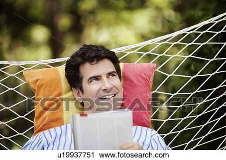Stock Image - Close-up of a mature man lying in a hammock and smiling. Fotosearch
