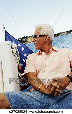 Close-up of a mature man sitting in a boat and looking sideways View Large Photo Image Picture - Close-up of a mature man sitting in a boat and looking sideways. Fotosearch