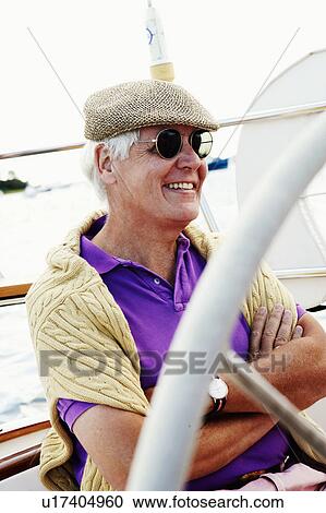 Stock Image - Close-up of a mature man sitting in a boat and smiling. Fotosearch