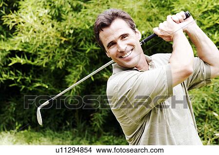 Picture - Close-up of a mature man swinging a golf club. Fotosearch