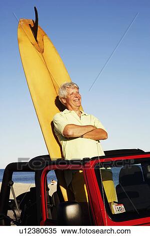 Mature man leaning against a surfboard in a sports utility vehicle View Large Photo Image Stock Photography - Mature man leaning against a surfboard in a sports utility vehicle. Fotosearch