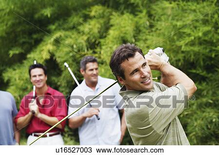 Mature man swinging a golf club with his friends standing behind him View Large Photo Image Stock Image - Mature man swinging a golf club with his friends standing behind him. Fotosearch