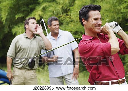 Mature man swinging a golf club with his friends standing behind him View Large Photo Image Stock Photography - Mature man swinging a golf club with his friends standing behind him. Fotosearch