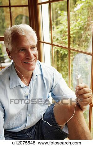 Stock Photo - Mature man wearing headphones and listening to music. Fotosearch
