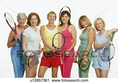 Stock Image - Portrait of a group of mature women holding tennis rackets and tennis balls. Fotosearch