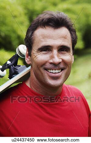 Portrait of a mature man carrying a skateboard on his shoulder and smiling View Large Photo Image Stock Image - Portrait of a mature man carrying a skateboard on his shoulder and smiling. Fotosearch