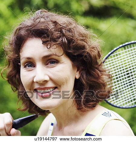 Stock Photo - Portrait of a mature woman holding a badminton racket and smiling. Fotosearch