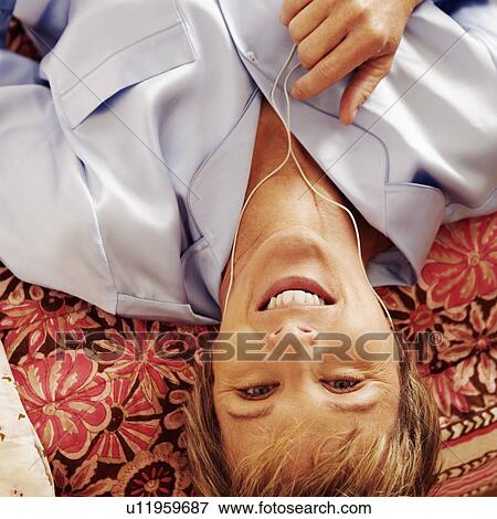 Portrait of a mature woman lying on the bed and listening to music on headphones View Large Photo Image Stock Photo - Portrait of a mature woman lying on the bed and listening to music on headphones. Fotosearch