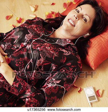 Portrait of a mature woman lying on the wooden floor and listening to an MP3 player View Large Photo Image Stock Photograph - Portrait of a mature woman lying on the wooden floor and listening to an MP3 player. Fotosearch